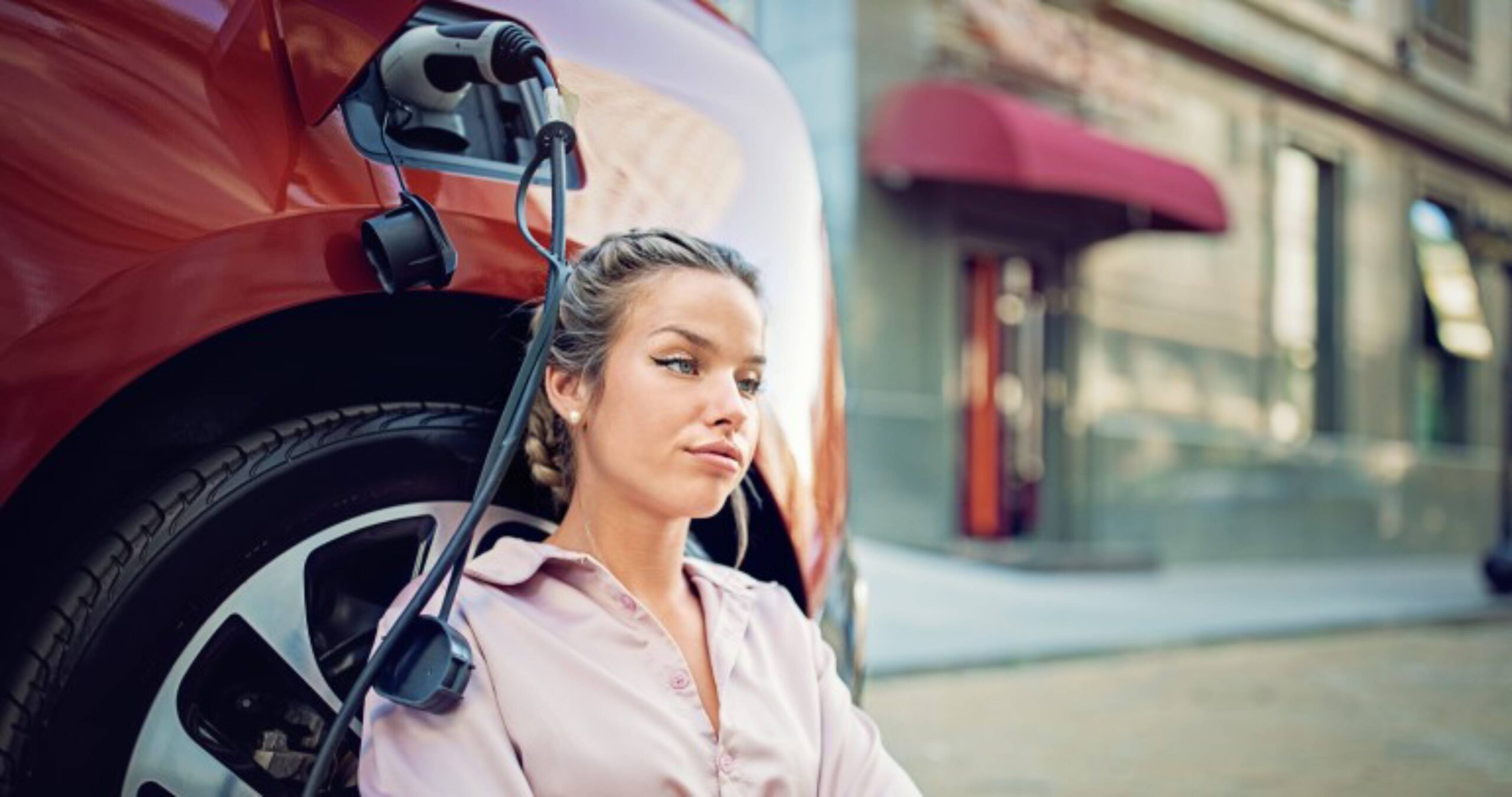 A woman relaxes beside an electric vehicle.