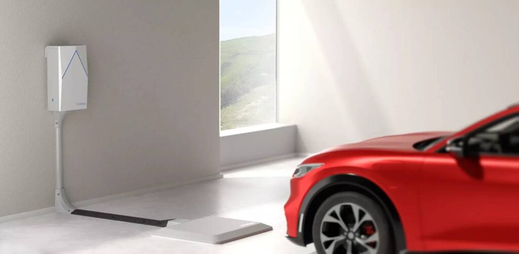A sleek red electric car parked beside a wall-mounted charging unit.