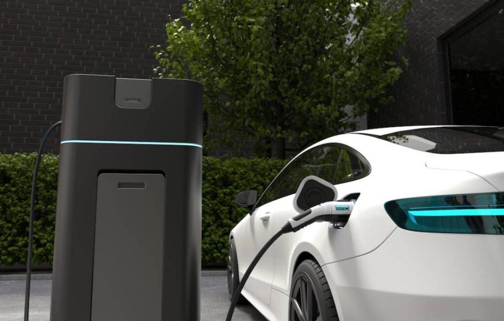 A white electric car plugged into a sleek black charging station.