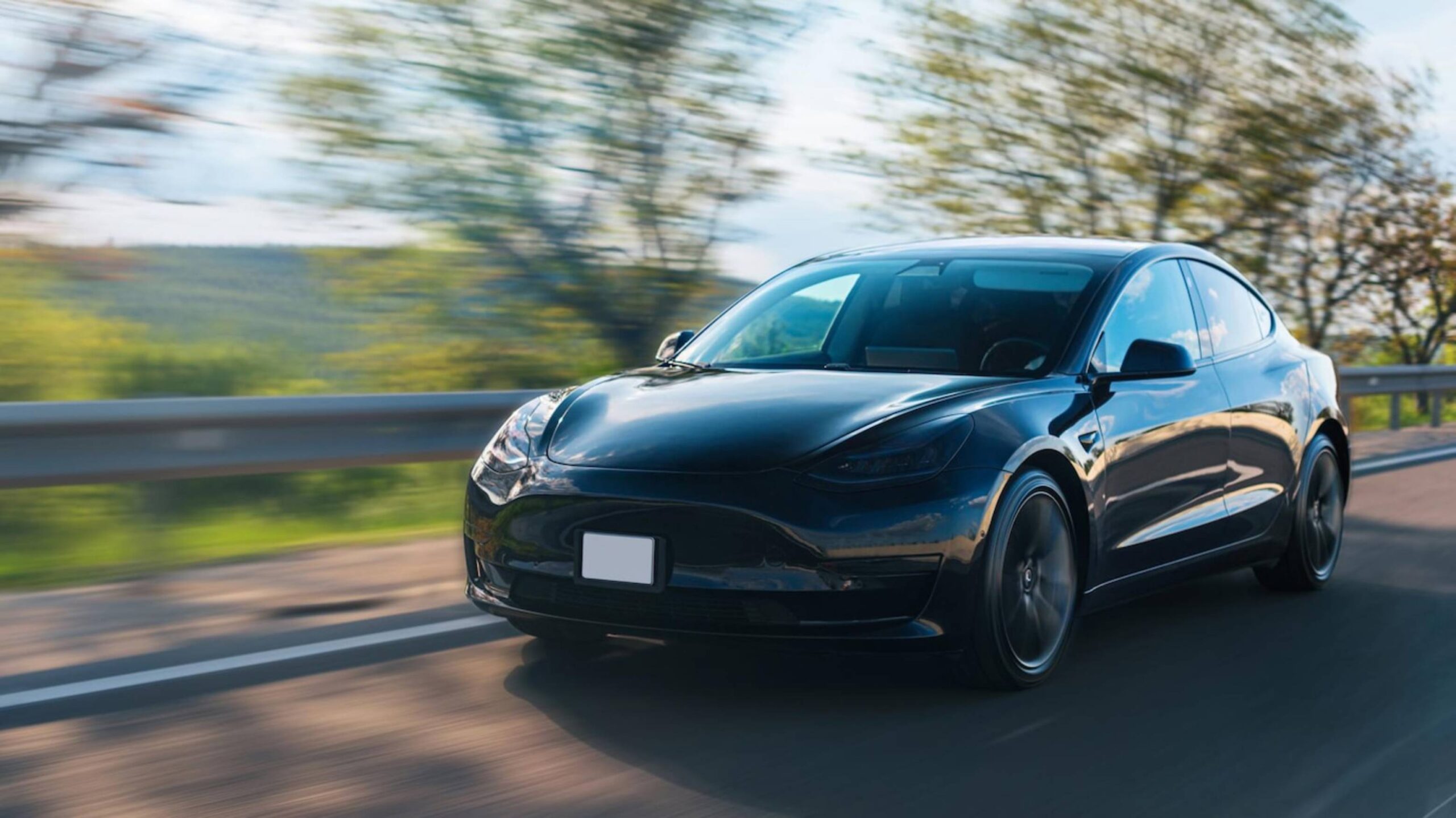 A sleek black car speeds along a winding road.