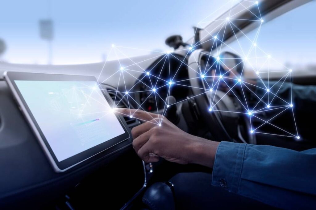 A driver's hand interacts with a touchscreen inside a car.