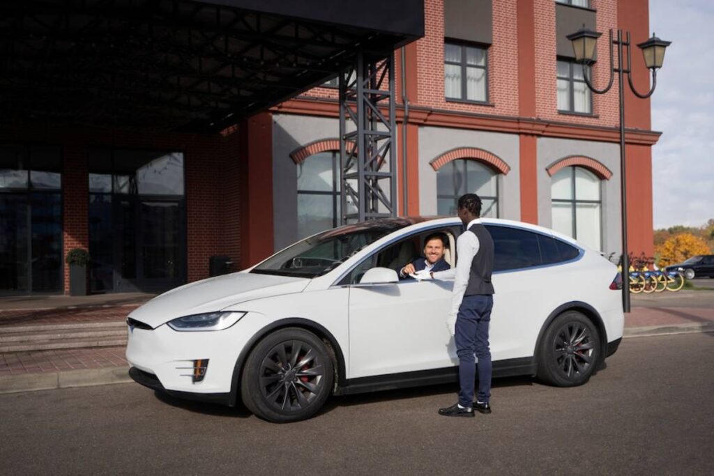 A white Tesla Model X parked outside a modern building.
