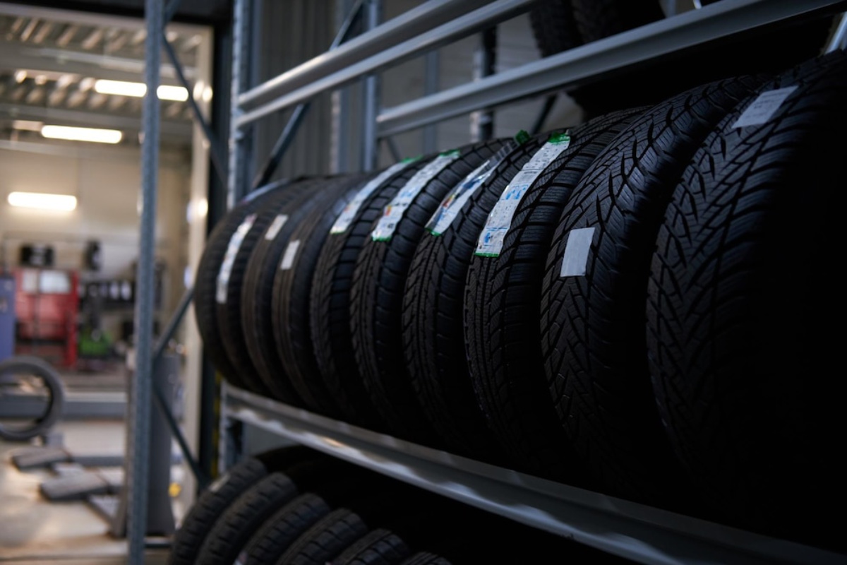  Row of new car tyres on a rack in an automotive workshop, labels visible.