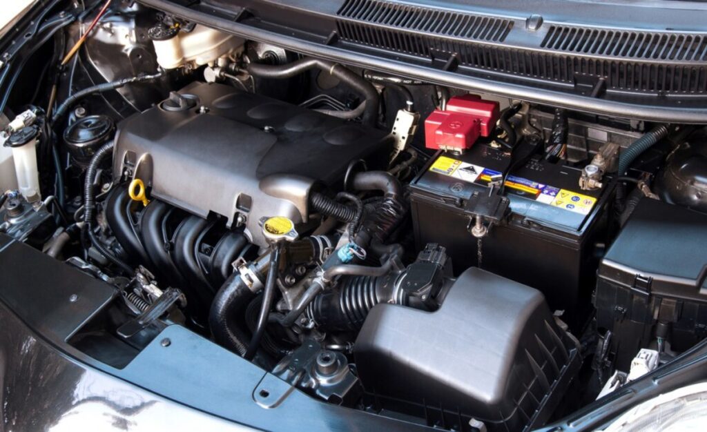 A car engine is visible with the hood open, showcasing the internal components and mechanics of the vehicle.