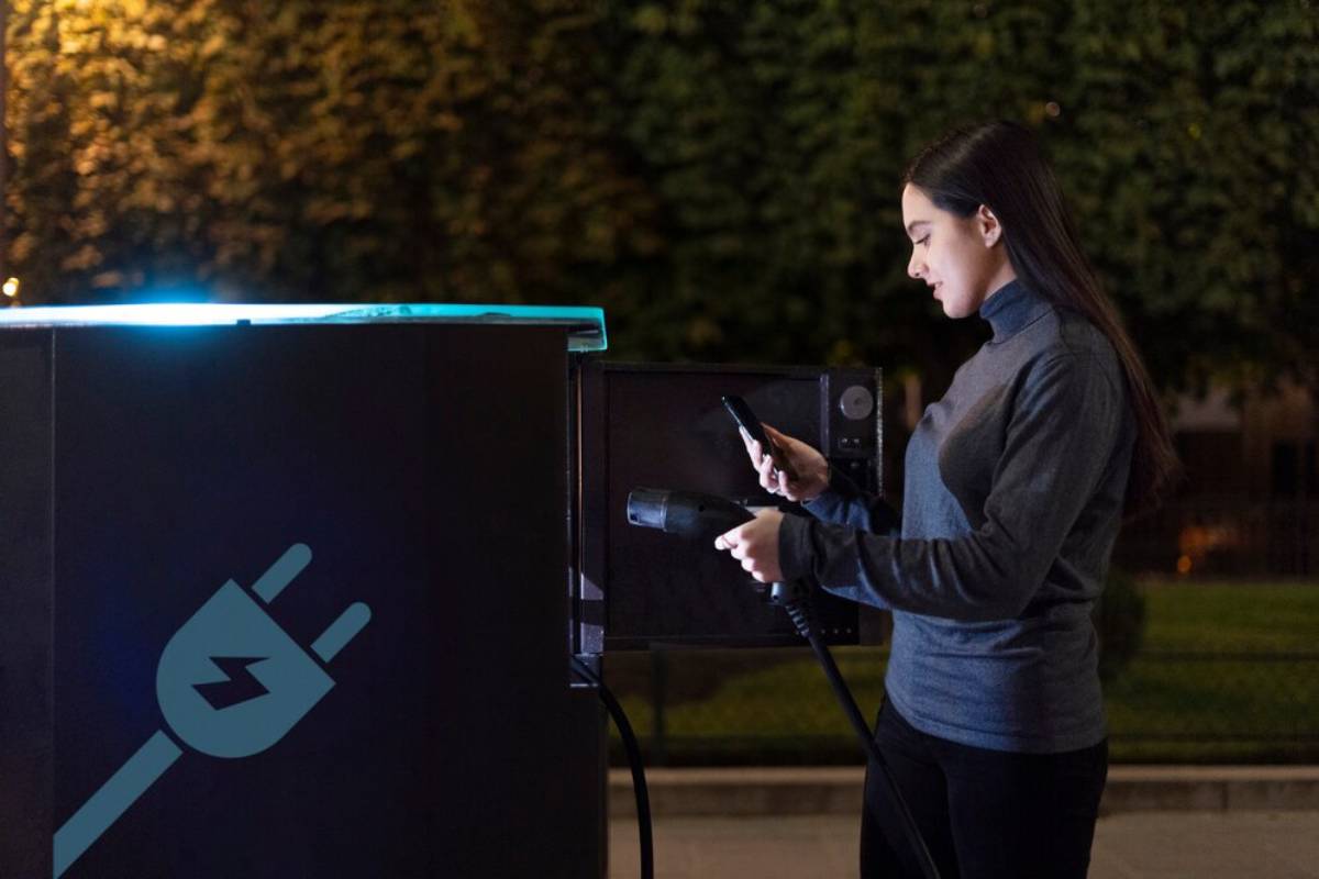  A woman stands beside her electric car, using her phone to monitor the charging process.
