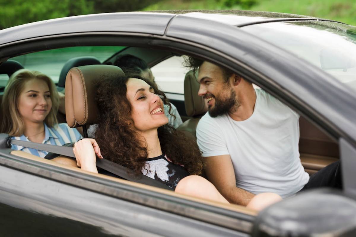  A man and woman sit together in the back seat of a car, engaged in conversation.